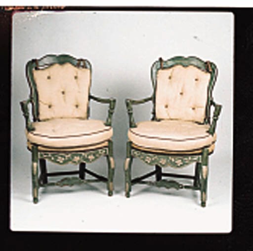 A PAIR OF LOUIS XV PROVINCIAL-STYLE IVORY AND GREEN PAINTED FAUTEUILS Each with a scalloped ladder bacq and outcurved arms around a rosette carved apron and Cabriole legs joined by stretches, upholstered in a beige-colored coarsely woven linen.