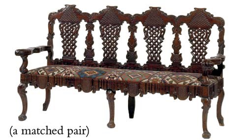 A MATCHED PAIR OF SPANISH COLONIAL CARVED HARDWOOD QUADRUPLE CHAIR BACK SETTEES