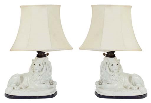 A PAIR OF WHITLE GLAZED CERAMIC LIONS MOUNTED AS LAMPS,