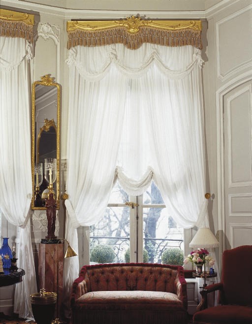 A SET OF NINE GILT COMPOSITION WINDOW PELMETS AND NINE PAIRS OF WHITE COTTON CURTAINS