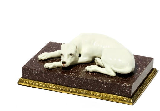 A WHITE PORCELAIN MODEL OF A RECUMBENT DOG