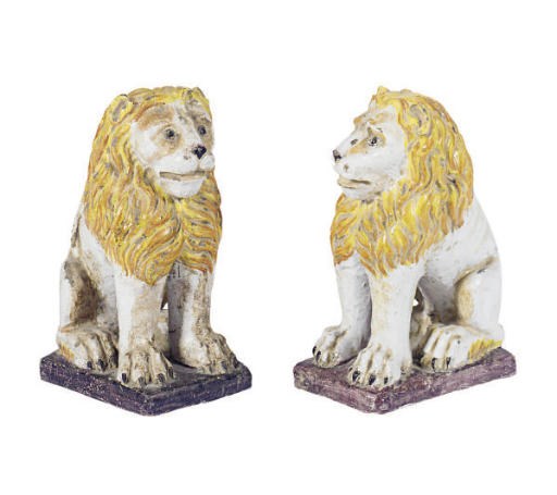 A PAIR OF TIN-GLAZED EARTHENWARE MODELS OF SEATED LIONS,