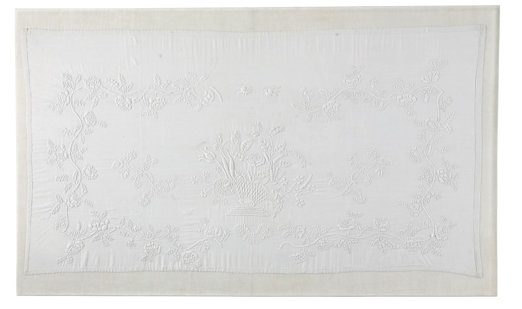 A WHITE TRAPUNTO COTTON DRESSING TABLE COVER