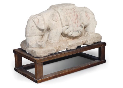 A LARGE STONE SCULPTURE OF A RECUMBENT ELEPHANT