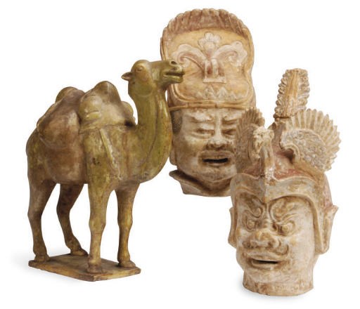 A PAIR OF CHINESE POTTERY HEADS OF GUARDIANS AND A POTTERY FIGURE OF A CAMEL,