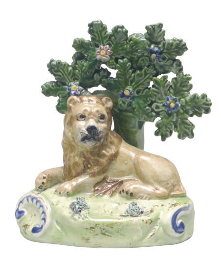 A STAFFORDSHIRE PEARLWARE BOCAGE MODEL OF A RECUMBENT LION,