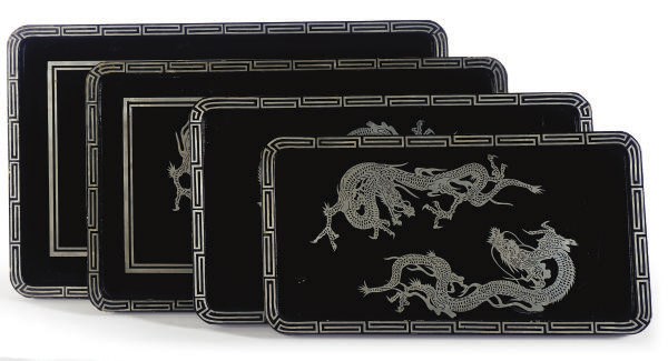 A SET OF FOUR SILVER AND BLACK LACQUERED NESTING SERVING TRAYS,