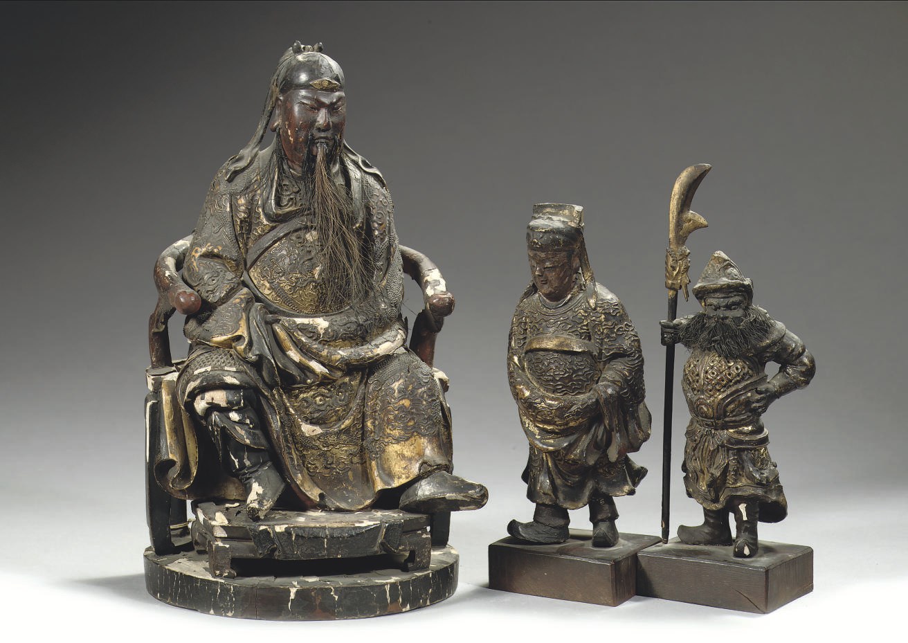 A Chinese lacquered and gilt wood figure of Guandi and two attendants
