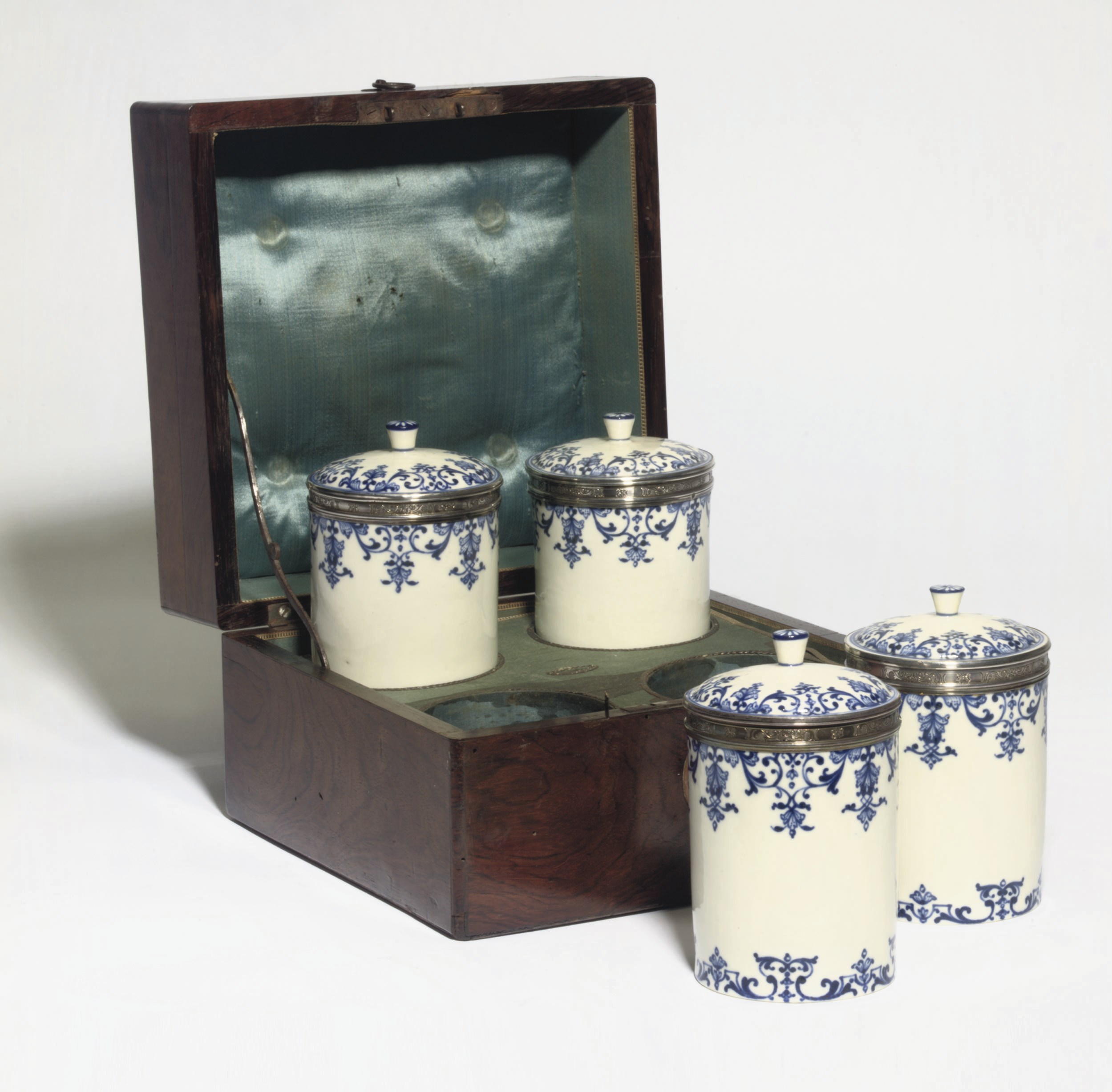A SET OF FOUR LOUIS XV SILVER-MOUNTED PORCELAIN POMMADE-POTS AND COVERS WITH ROSEWOOD PARQUETRY CASKET