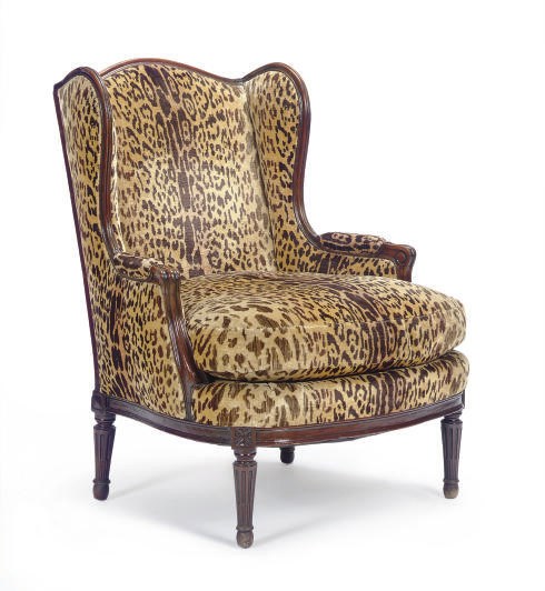 A LOUIS XVI WALNUT AND FAUX-LEOPARD SKIN UPHOLSTERED WINGBACK BERGERE,
