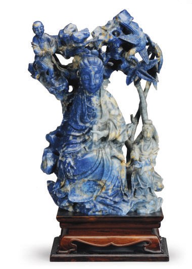 A CHINESE CARVED SODALITE GUANYIN AND ACOLYTES ON A WOOD STAND
