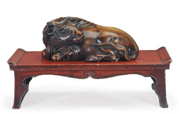A CHINESE CARVED HARDWOOD FIGURE OF A RECUMBENT WATER BUFFALO ON A LACQUER STAND,