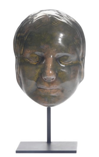 A CONTINENTAL GREEN-GLAZED EARTHENWARE MODEL OF A WOMAN'S FACE ON A STAND,