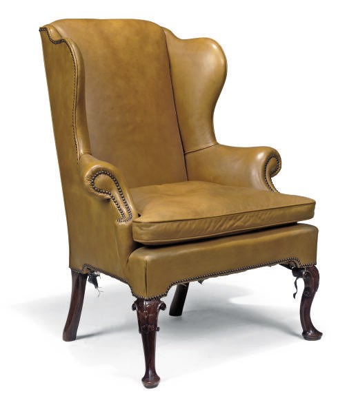 A LEATHER AND WALNUT WING ARMCHAIR