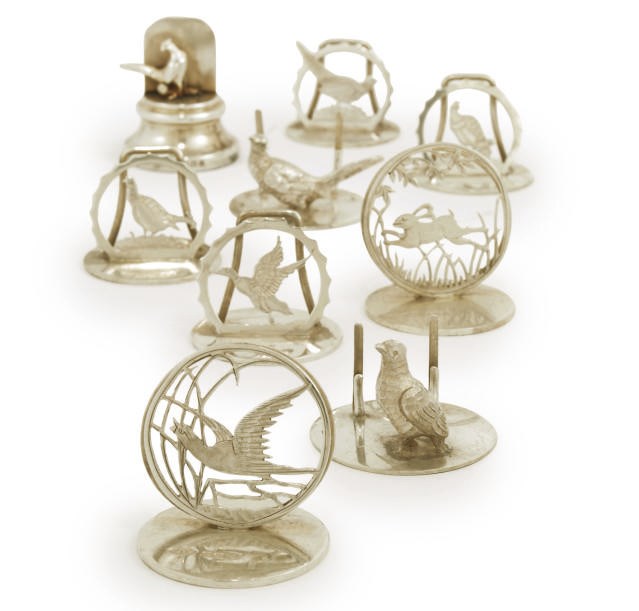 A GROUP OF NINE EDWARDIAN AND LATER NOVELTY SILVER MENU HOLDERS FEATURING GAME BIRDS OR ANIMALS