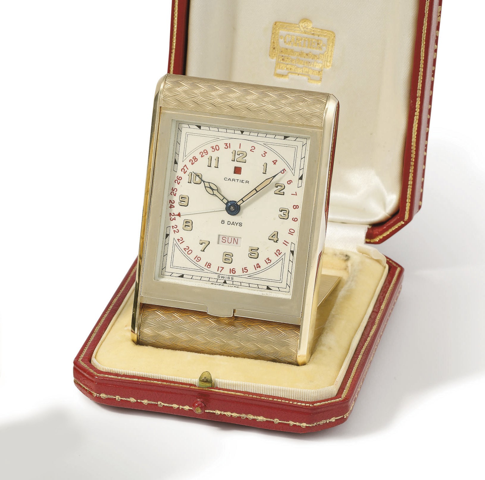 Cartier. A fine and unusual 9K gold hinged 8-day calendar bedside timepiece with power reserve and original box