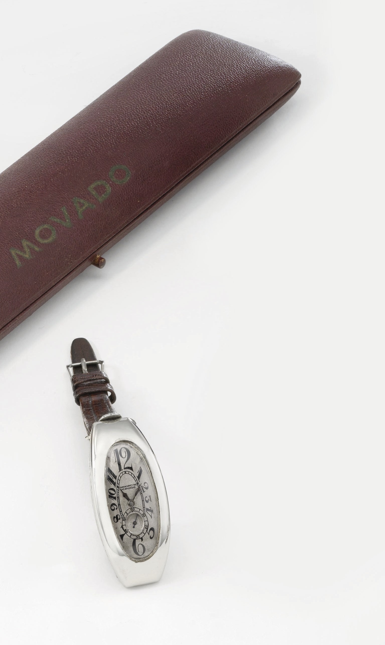 Movado. An unusual, large and early 18K white gold tonneau-shaped curved hinged wristwatch with box