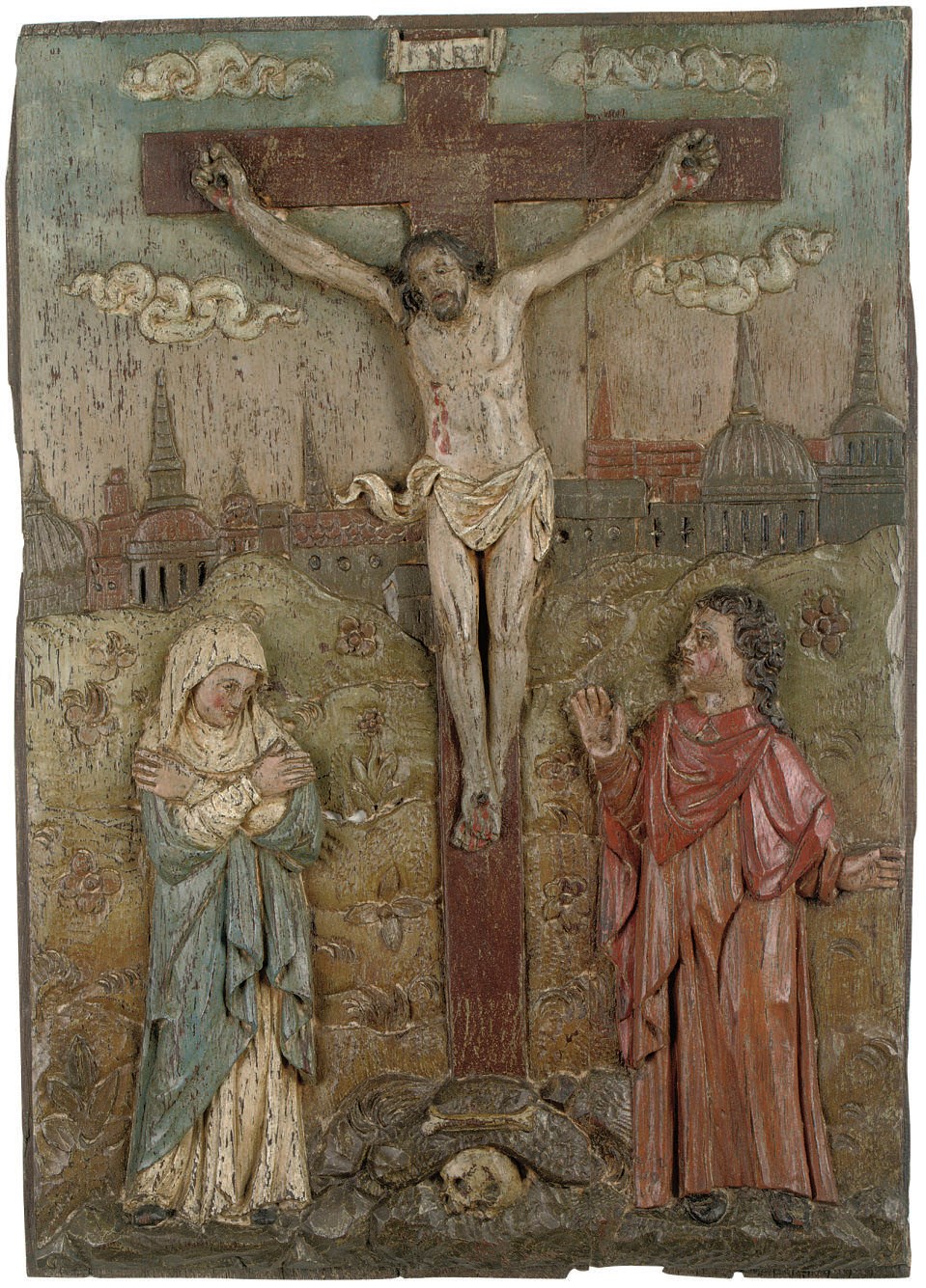 A polychrome carved wood relief of the crucified Christ with saints Mary and John