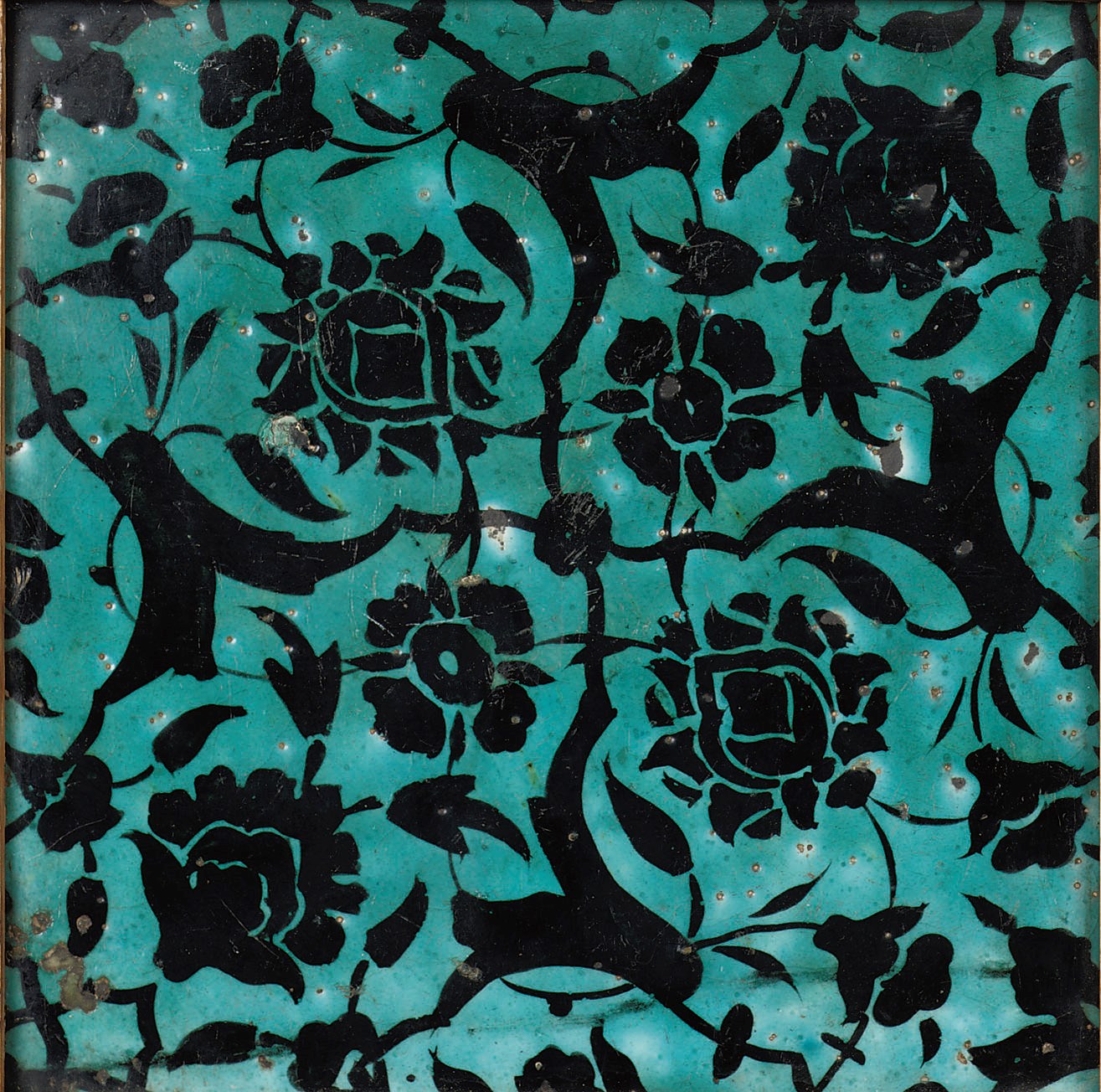 A square black and turquoise pottery tile