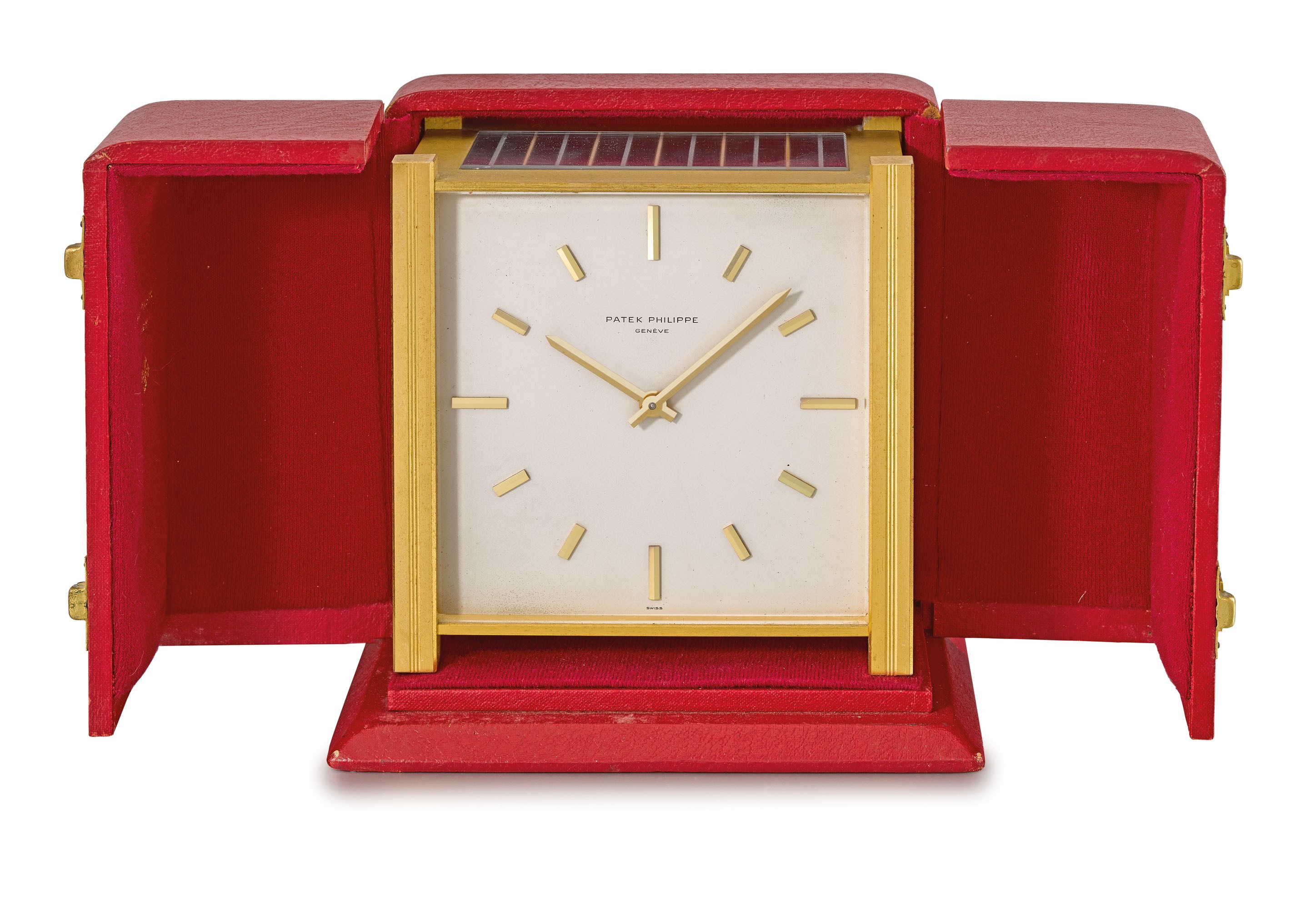 Patek Philippe. A gilt brass square-shaped solar-powered table clock with box